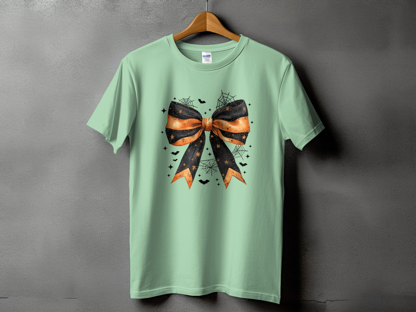 Mint green t-shirt with a Halloween bow graphic, spiders, bats, and stars.