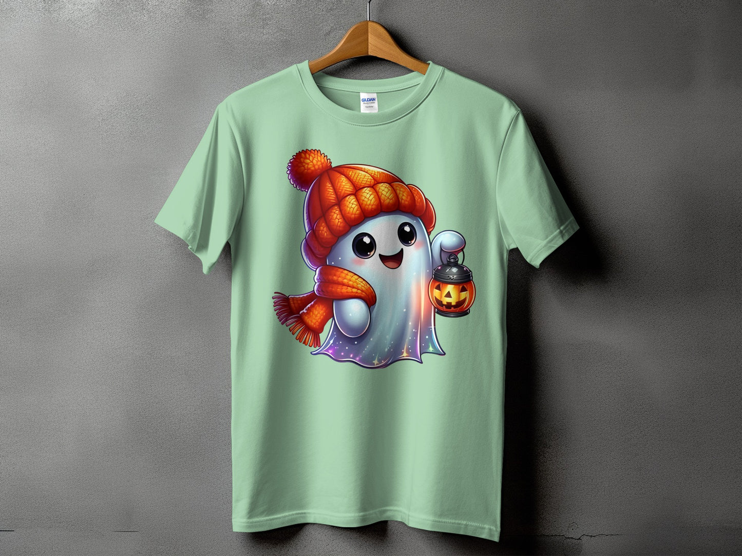 Mint green t-shirt with a cartoon ghost wearing a hat and scarf holding a jack-o-lantern.