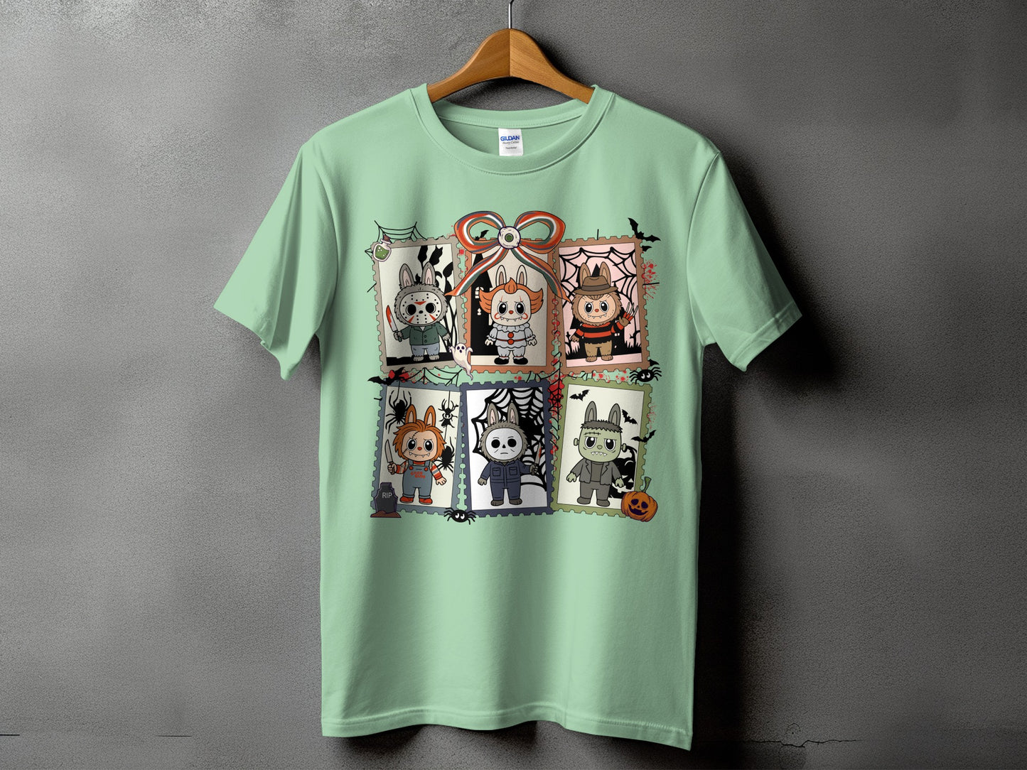 Light green t-shirt featuring six Halloween-themed cartoon characters in postage stamp frames.