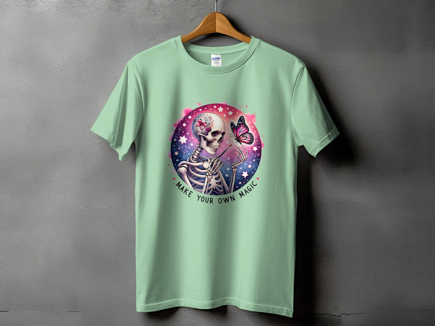 Mint green t-shirt with skeleton, butterfly, and text "Make Your Own Magic" graphic.