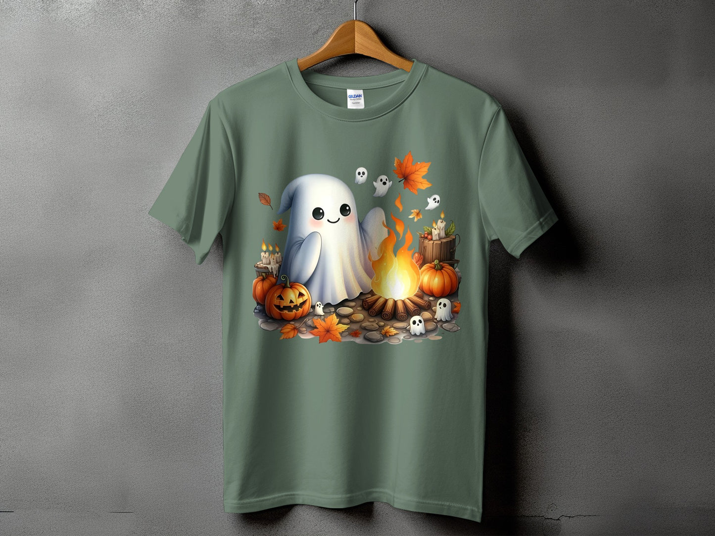 Cute ghost, pumpkins, campfire, and leaves Halloween graphic on a green t-shirt.