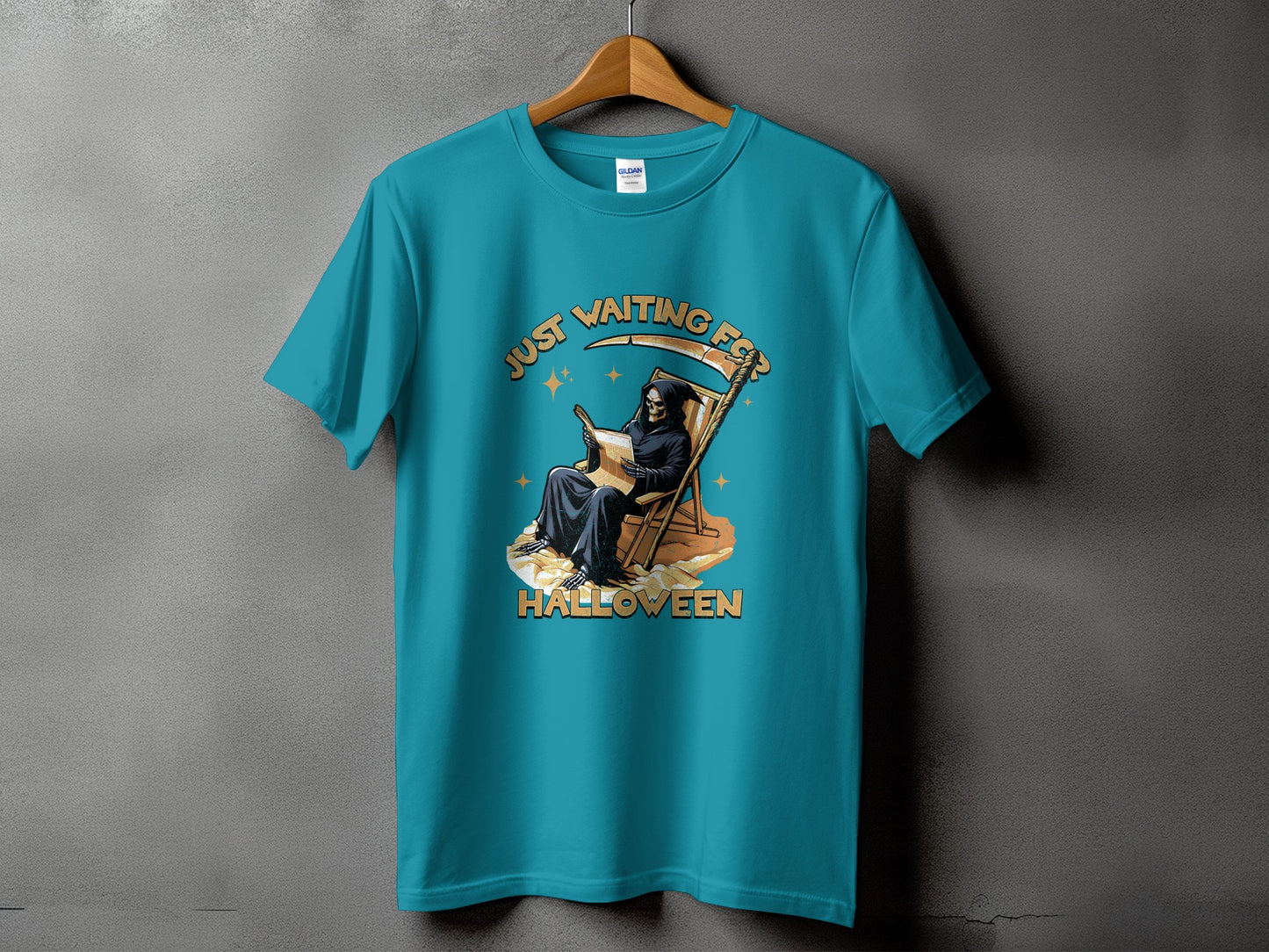 Grim Reaper in deck chair, "Just Waiting For Halloween" text on teal t-shirt.