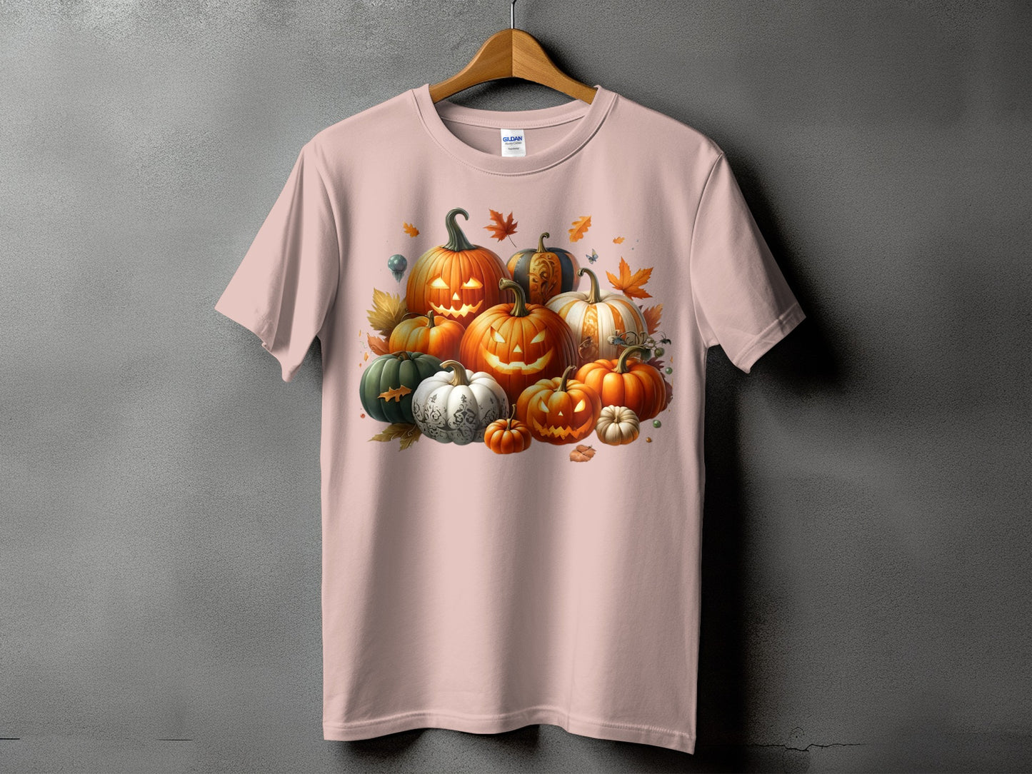 Pink t-shirt with a graphic of assorted carved and decorative pumpkins with autumn leaves.