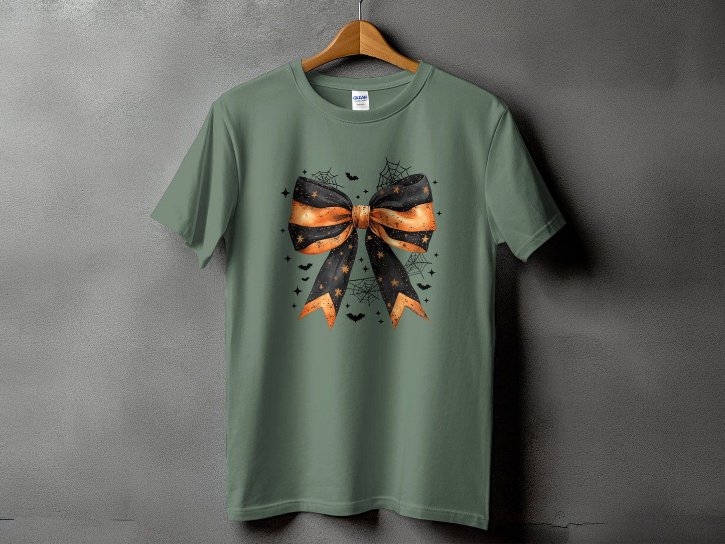 Green t-shirt with a Halloween-themed bow, bats, stars, and spiderwebs graphic.
