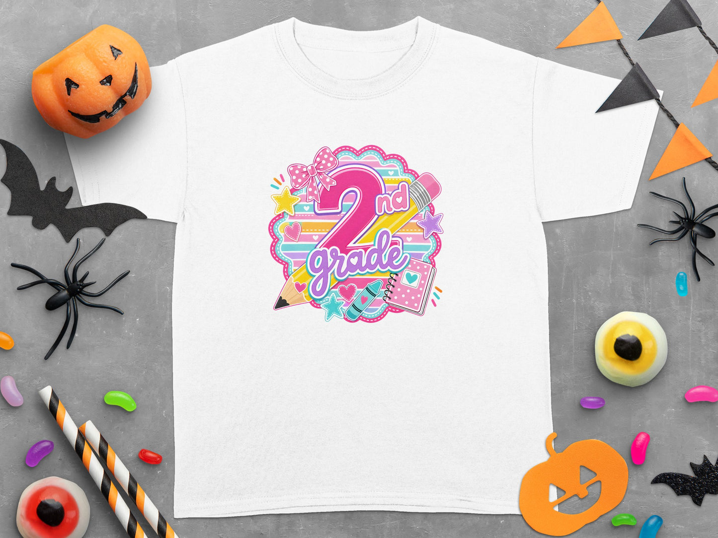 White t-shirt with "2nd grade" in colorful lettering, surrounded by school supplies and Halloween decorations.