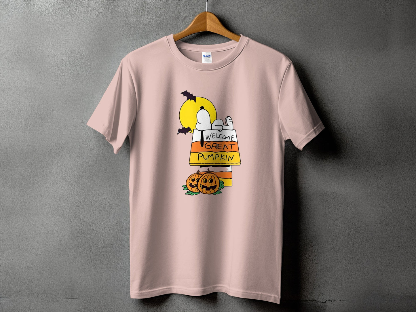 Pink t-shirt with Snoopy graphic saying "Welcome Great Pumpkin" and Halloween pumpkins.