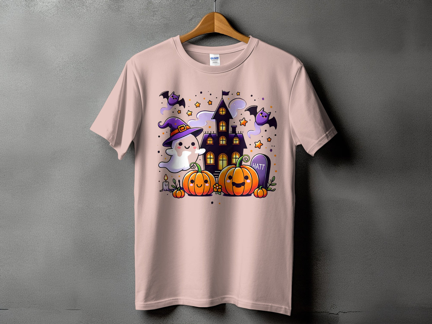 Pink t-shirt with a Halloween graphic featuring a ghost, pumpkins, bats, and a haunted house.