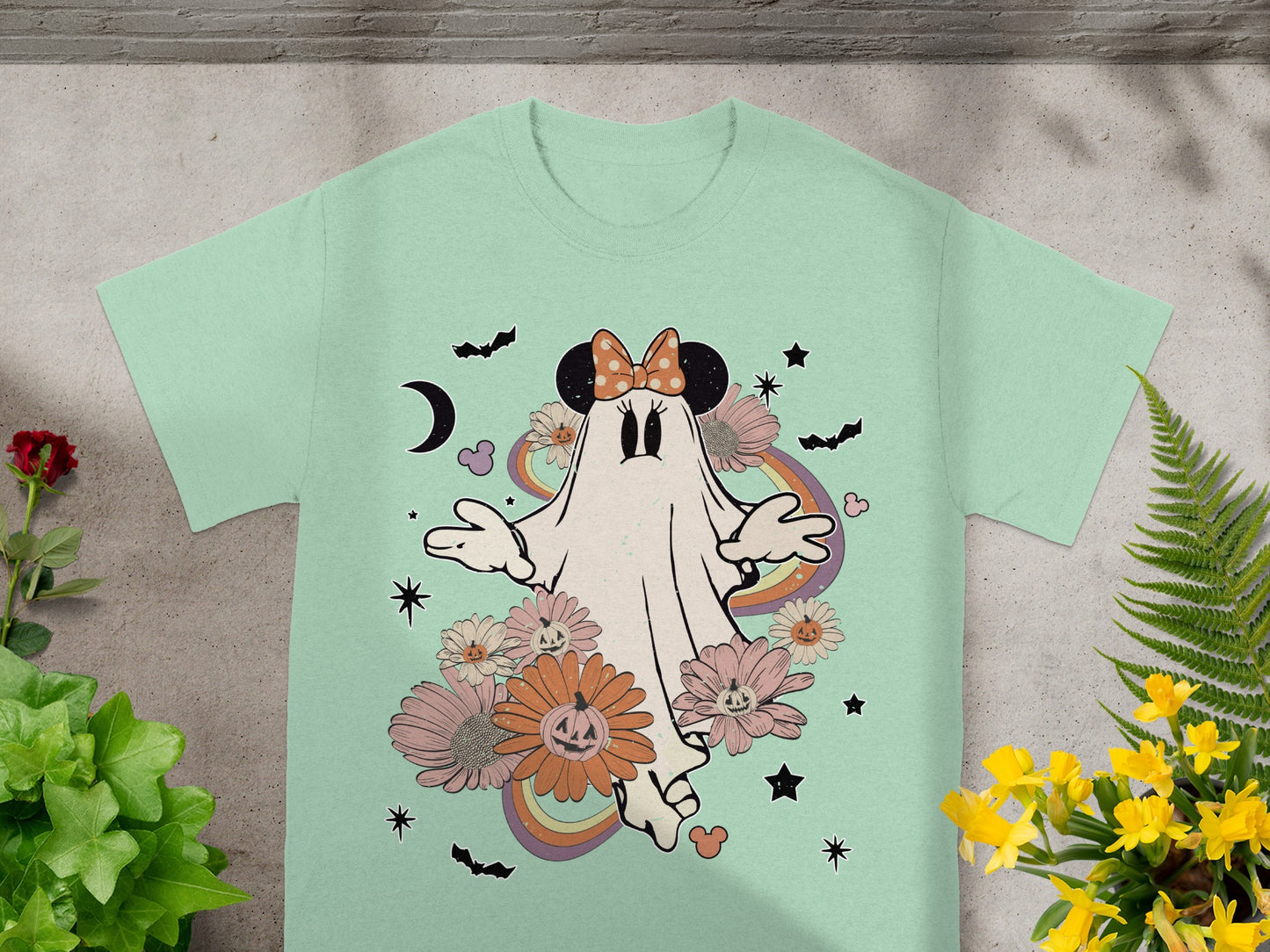 Ghost with Minnie Mouse ears and bow surrounded by flowers, pumpkins, bats, and rainbows.