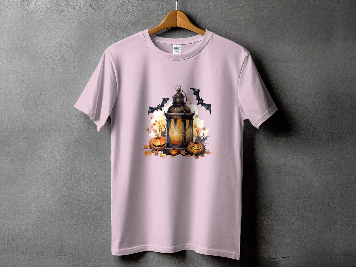 Pink t-shirt with a Halloween graphic of a lantern, pumpkins, bats, and autumn leaves.