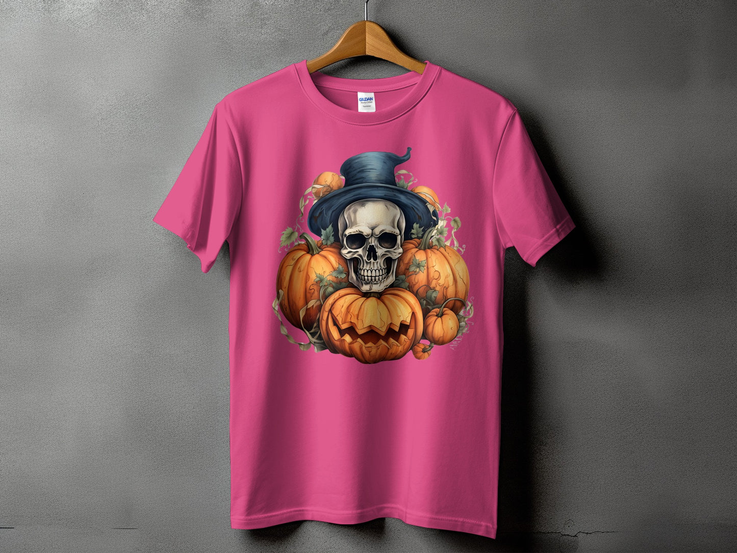 Pink t-shirt with a skull in a witch hat surrounded by pumpkins and vines.