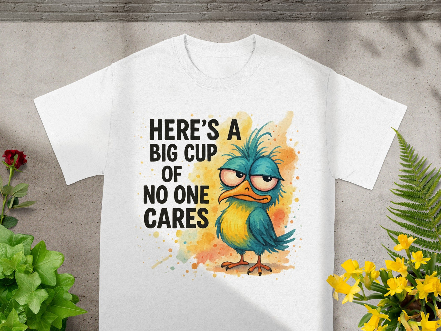 White t-shirt with a grumpy bird graphic and "Here's a big cup of no one cares" text.