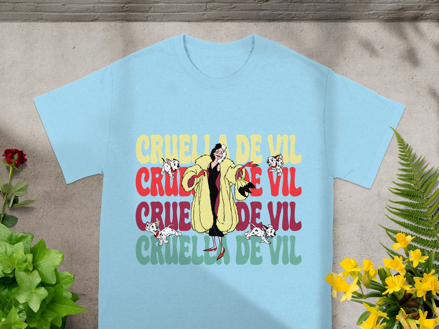 Light blue t-shirt with "Cruella De Vil" in colorful lettering and cartoon dogs.