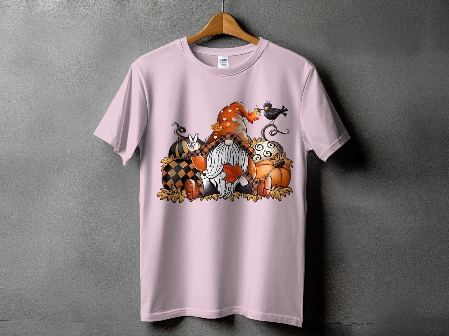 Gnome with pumpkins and fall leaves graphic on a pink t-shirt.
