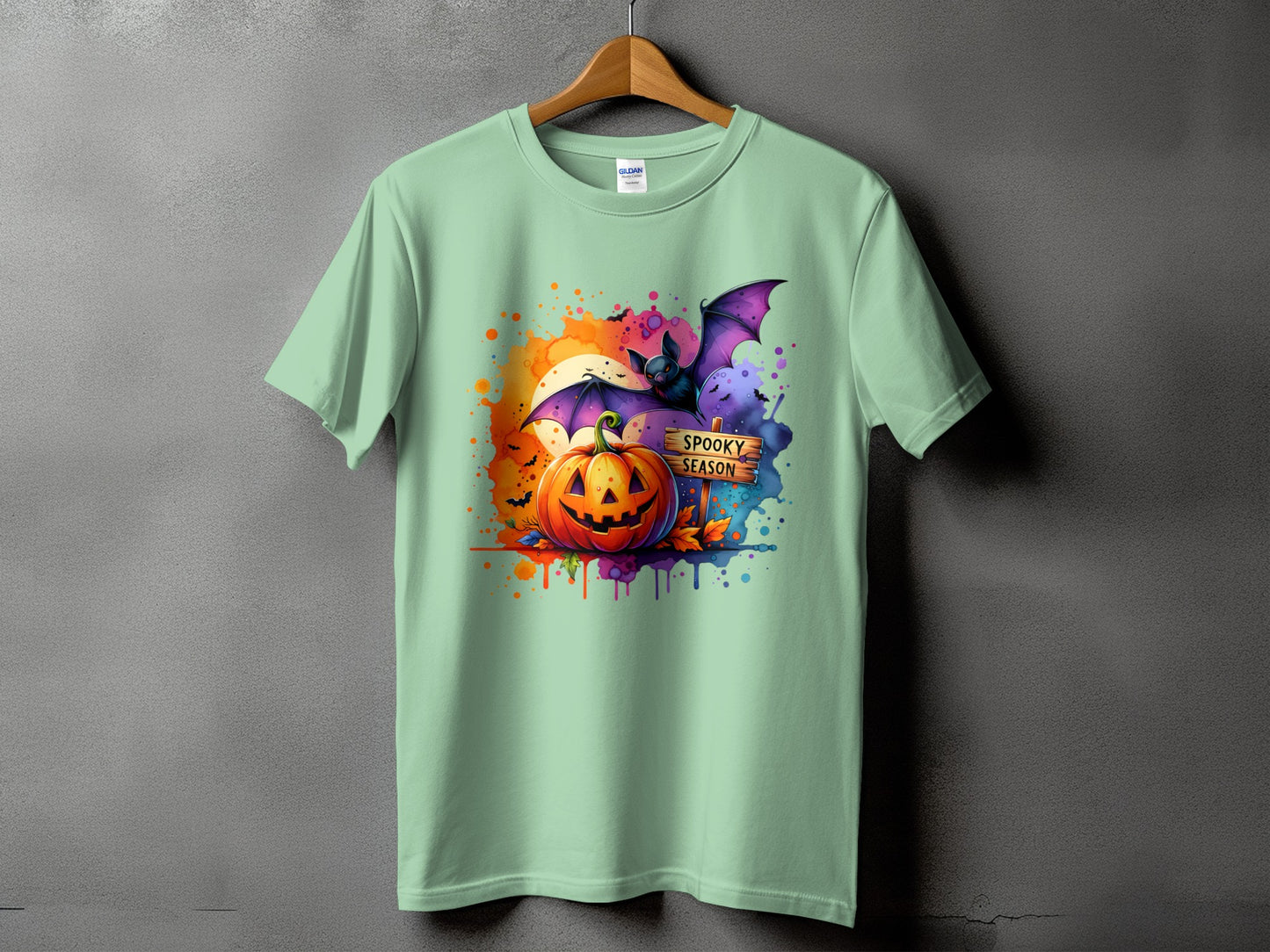 Green t-shirt with Halloween graphic of pumpkin, bat, and "Spooky Season" sign.