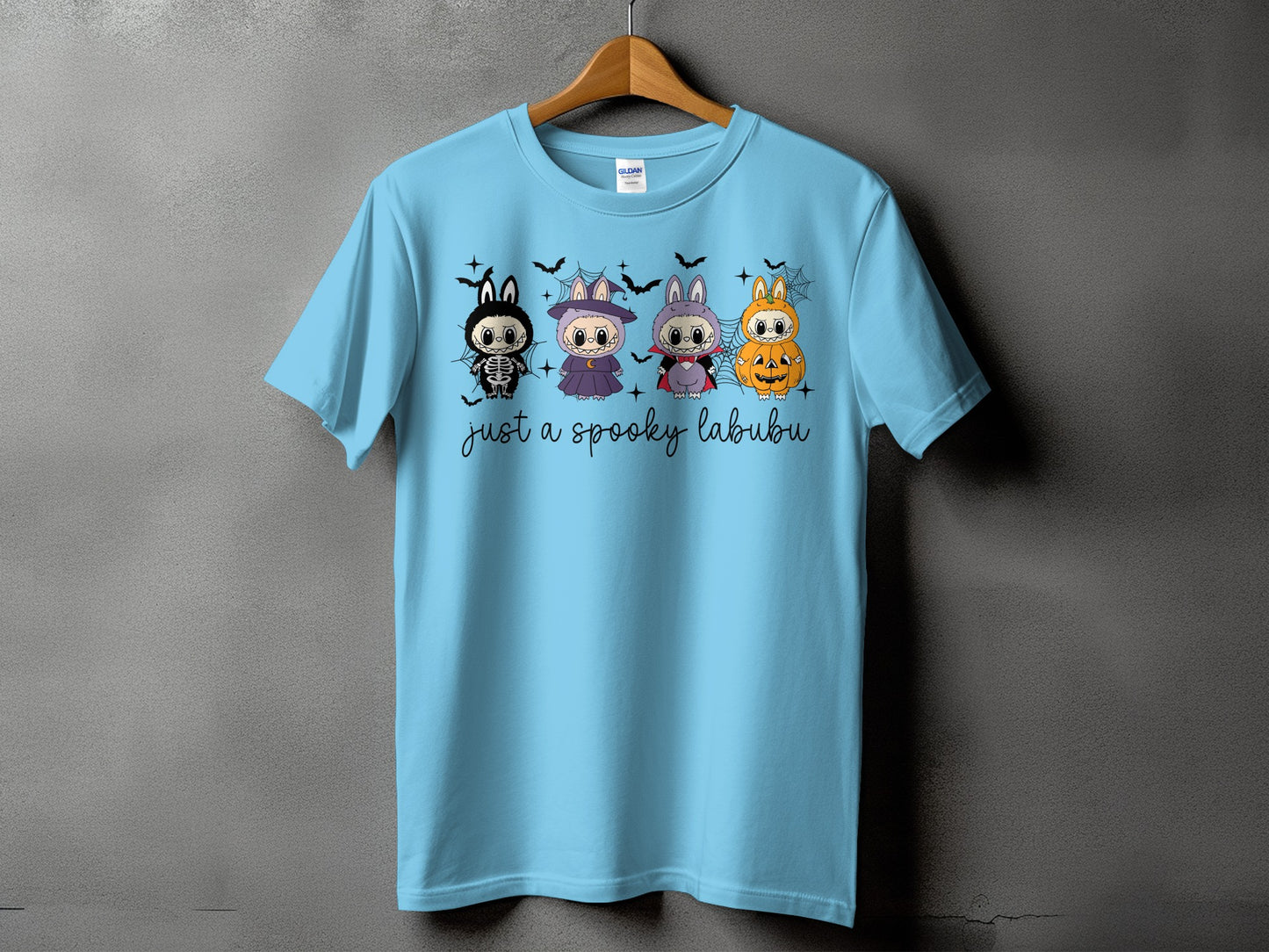 Light blue t-shirt with four Halloween-themed Labubu characters and "just a spooky labubu" text.