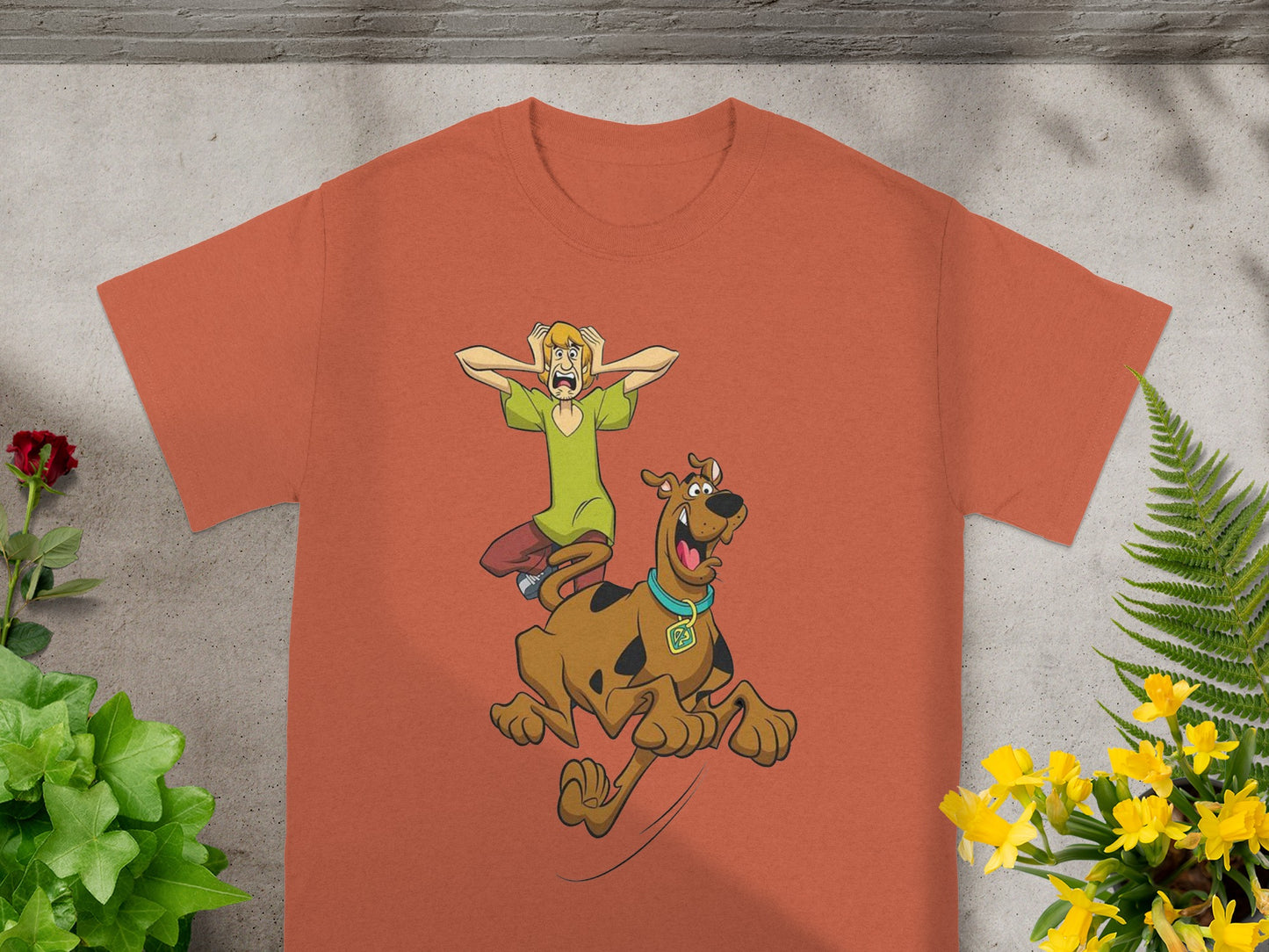 Scooby-Doo and Shaggy running in fear from an unseen threat on an orange t-shirt.
