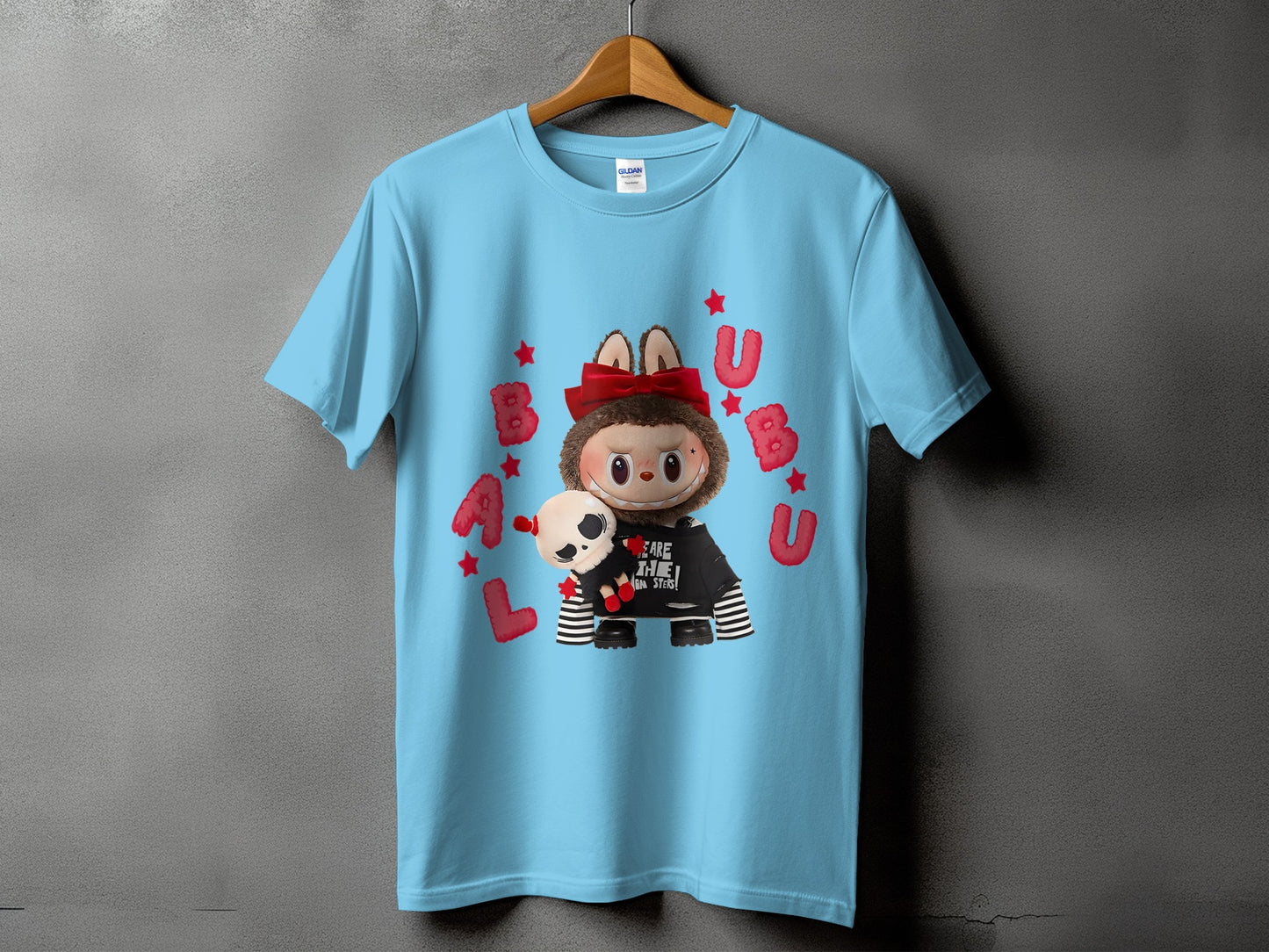 Light blue t-shirt with a cartoon monster, skull plush, and red lettering.
