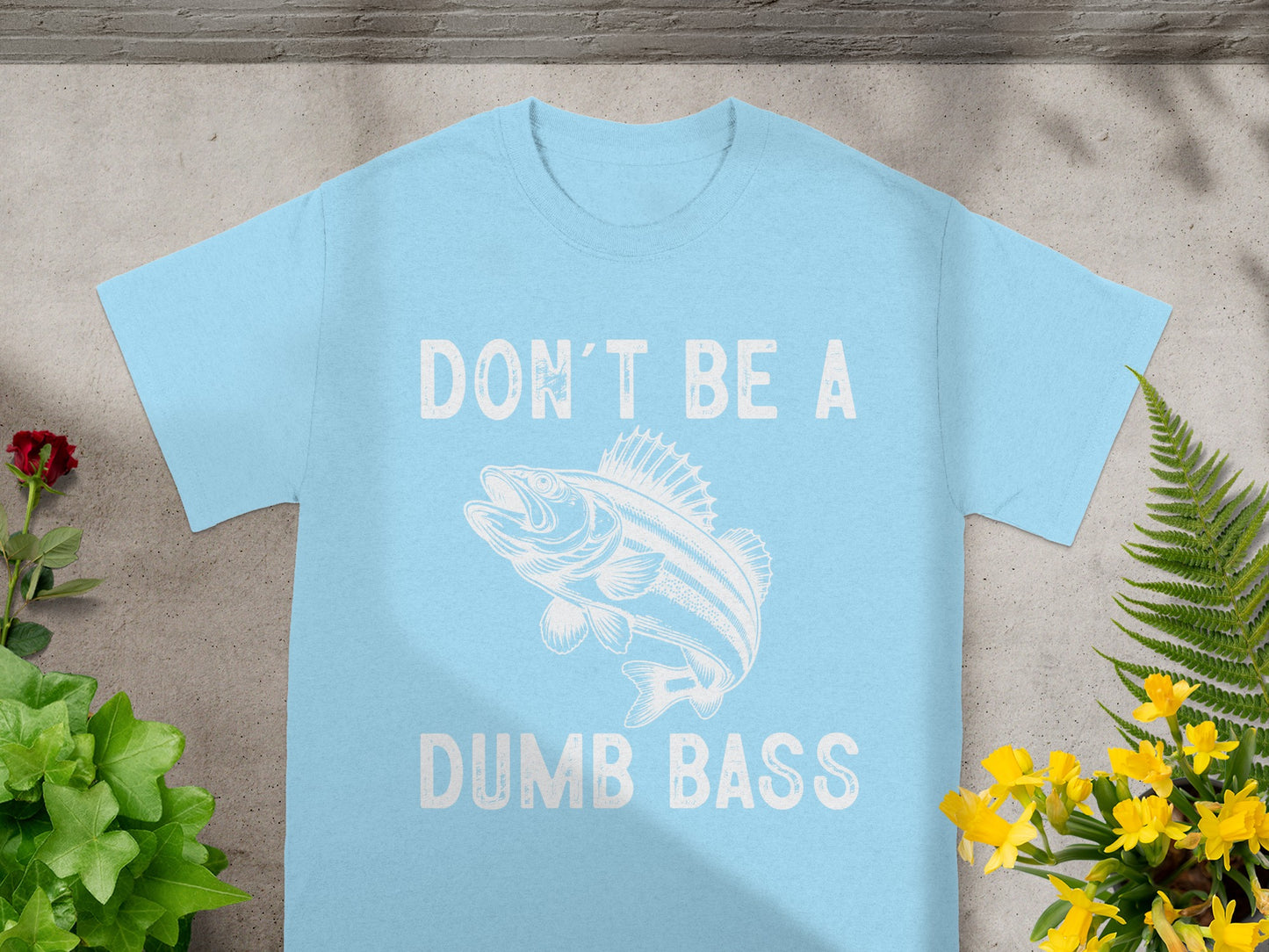 Light blue t-shirt with white text "DON'T BE A DUMB BASS" and a bass fish illustration.