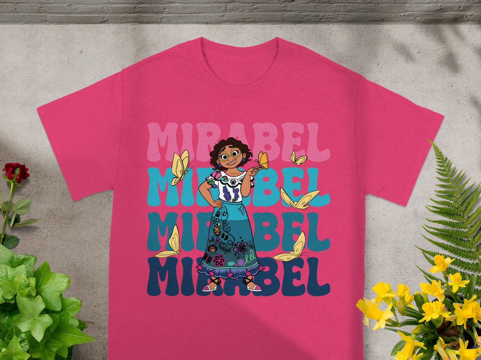 Mirabel from Encanto on a pink t-shirt with butterflies and colorful text.