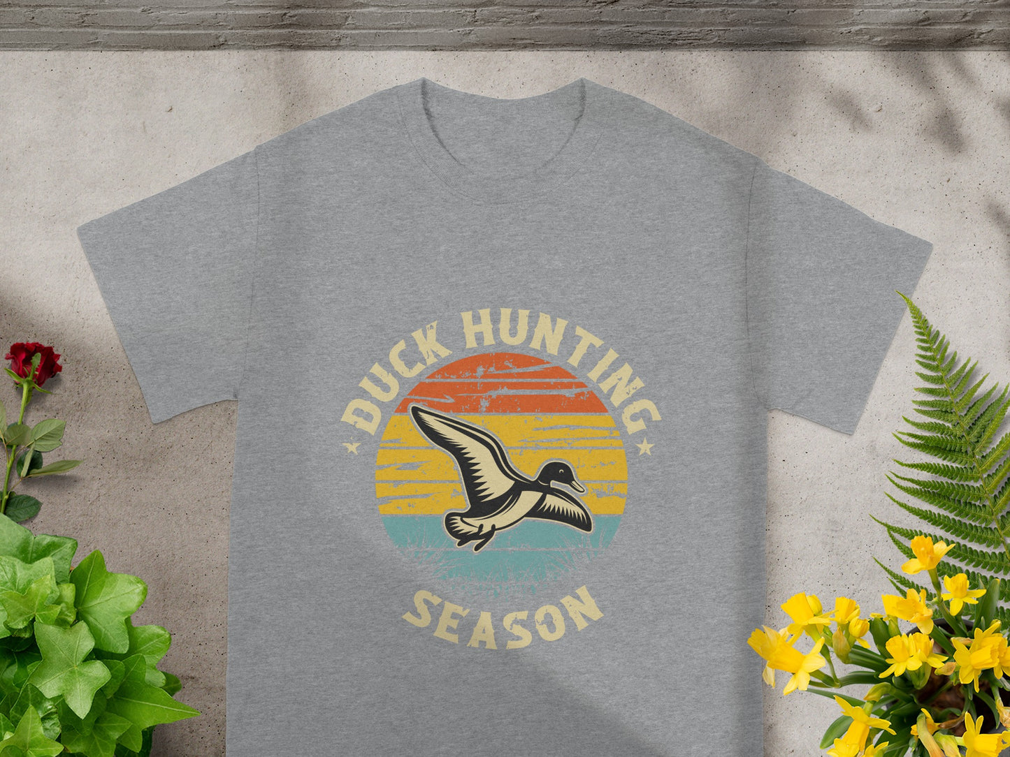 Grey t-shirt with "Duck Hunting Season" text and a duck illustration on a sunset background.