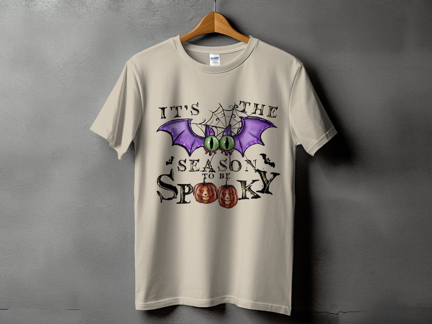 Light tan t-shirt with "It's the season to be spooky" text and Halloween graphics.