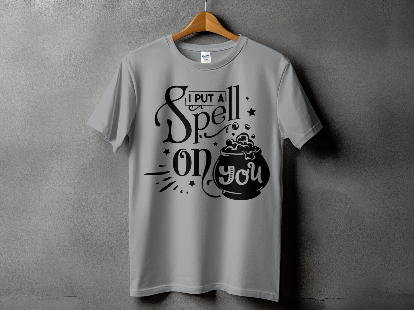 Gray t-shirt with black text and graphics that say "I put a spell on you" with a cauldron.