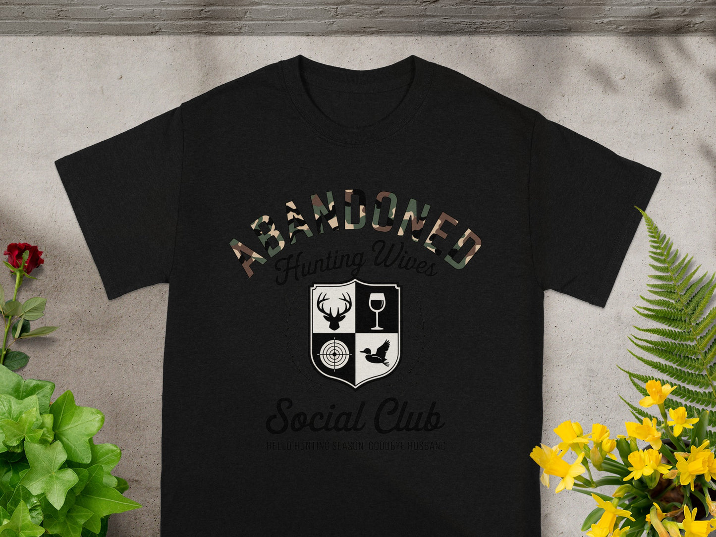 Black t-shirt with "ABANDONED Hunting Wives Social Club" text and graphics.