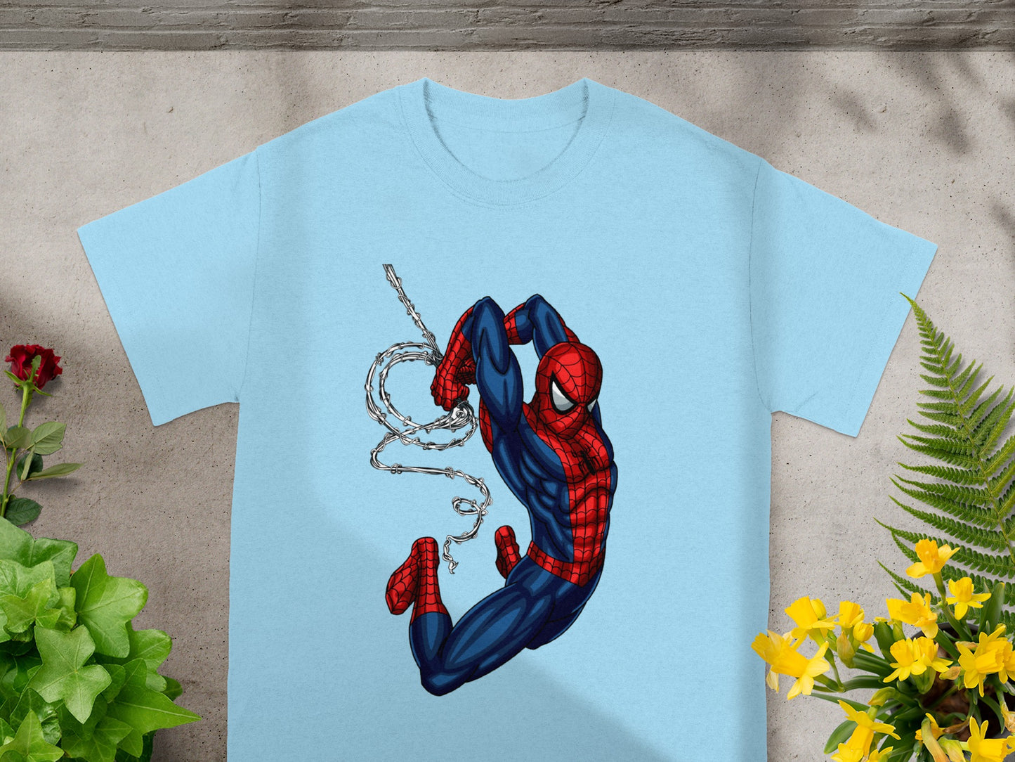 Spiderman suspended by web on light blue t-shirt.