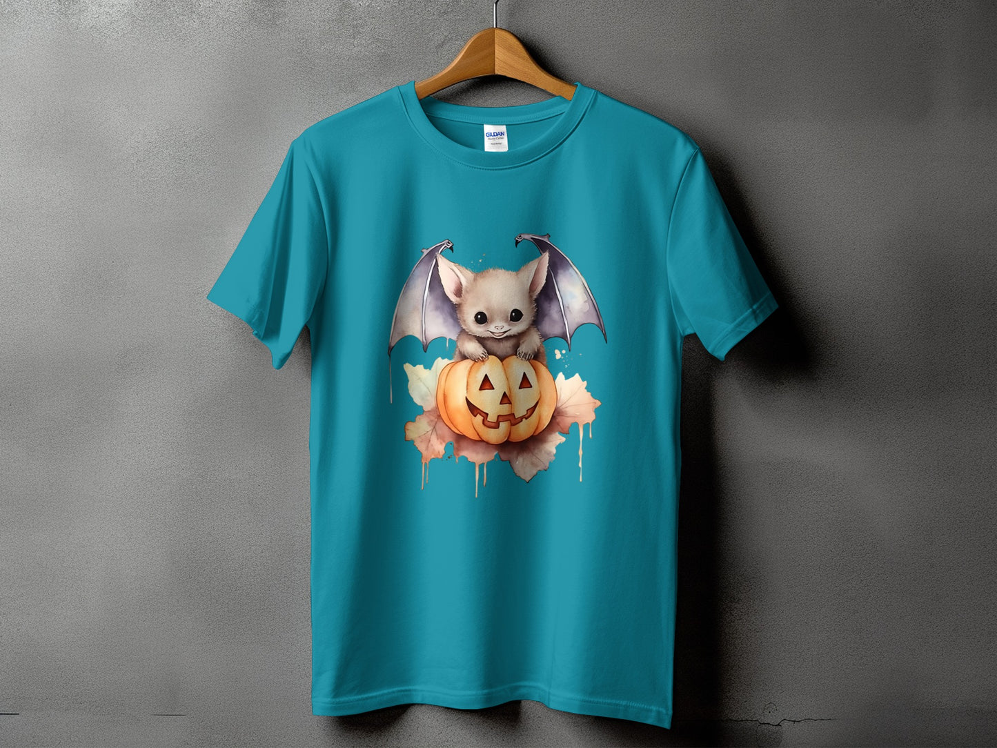Teal t-shirt with a watercolor graphic of a cute bat sitting on a jack-o'-lantern.