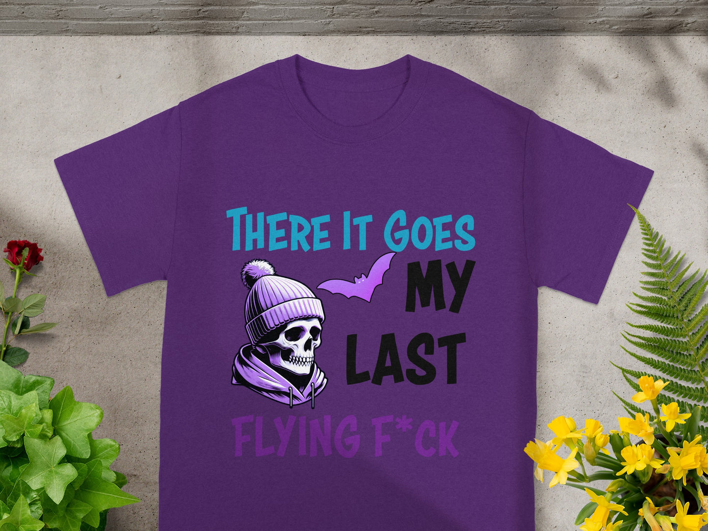 Purple t-shirt with skull wearing beanie, bat, and text: THERE IT GOES MY LAST FLYING F*CK.