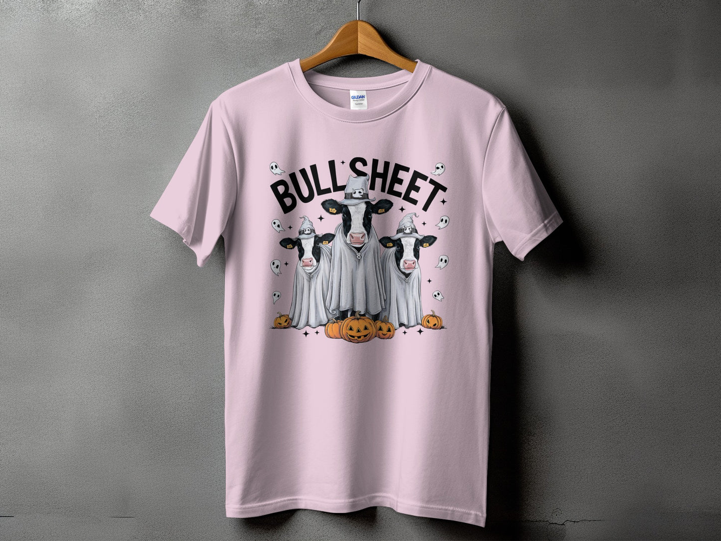 Pink t-shirt with three cows dressed as ghosts with pumpkins and the text "BULL SHEET".