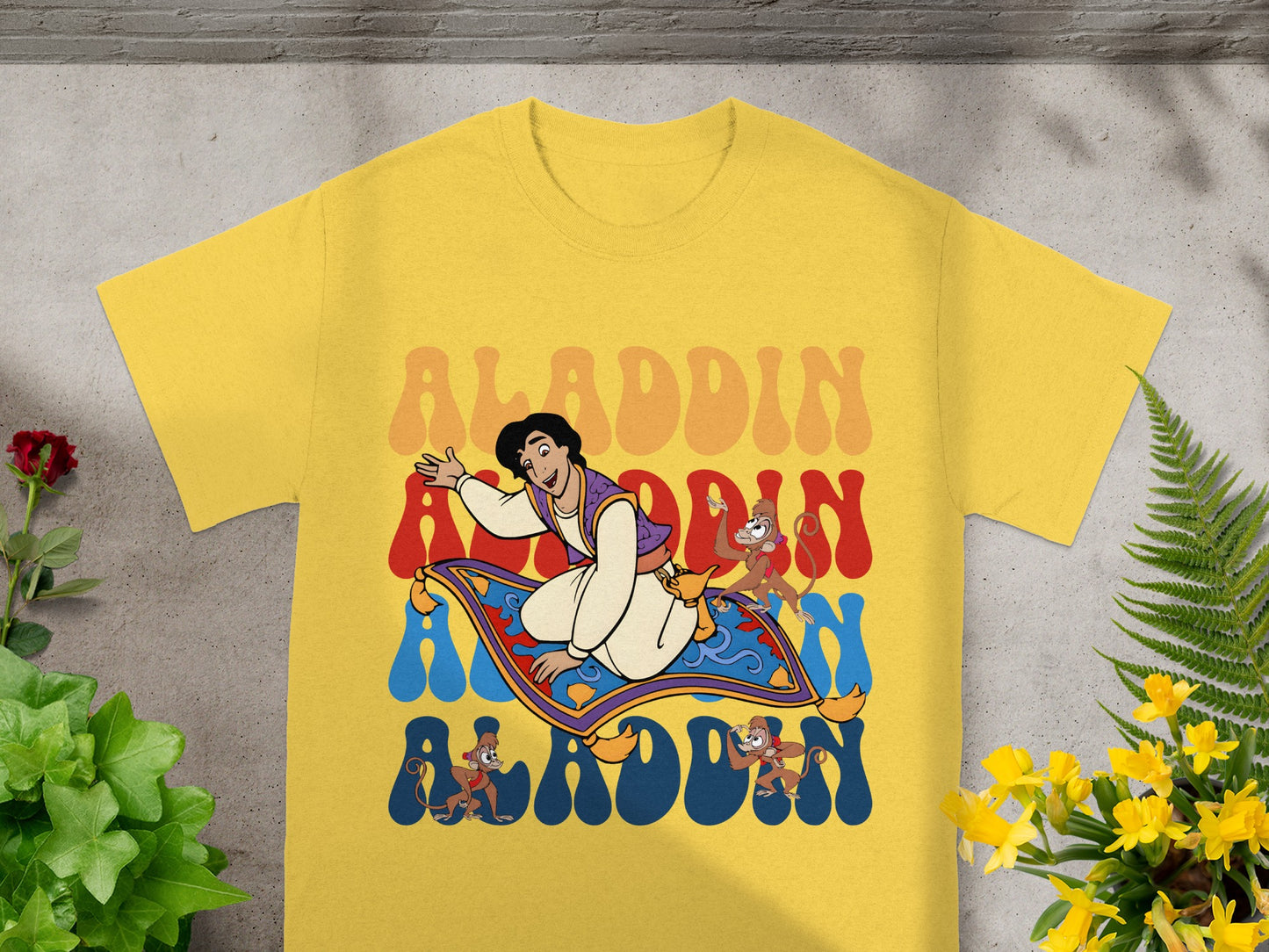 Aladdin and Abu riding a magic carpet with colorful wavy text.