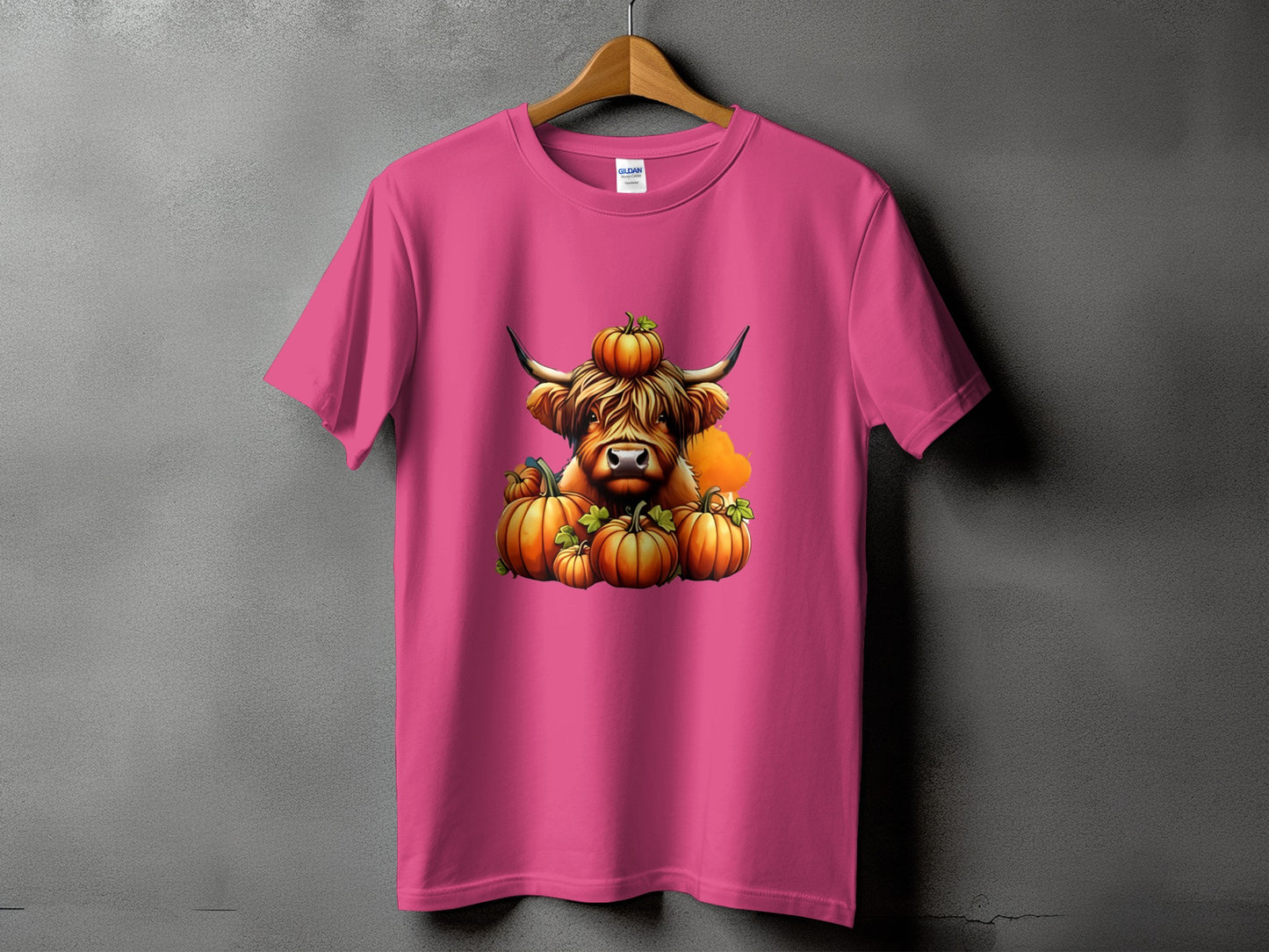 Pink t-shirt with a Highland cow and pumpkins graphic.