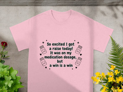 Pink t-shirt with text "So excited I got a raise today! It was on my medication dosage, but a win is a win."