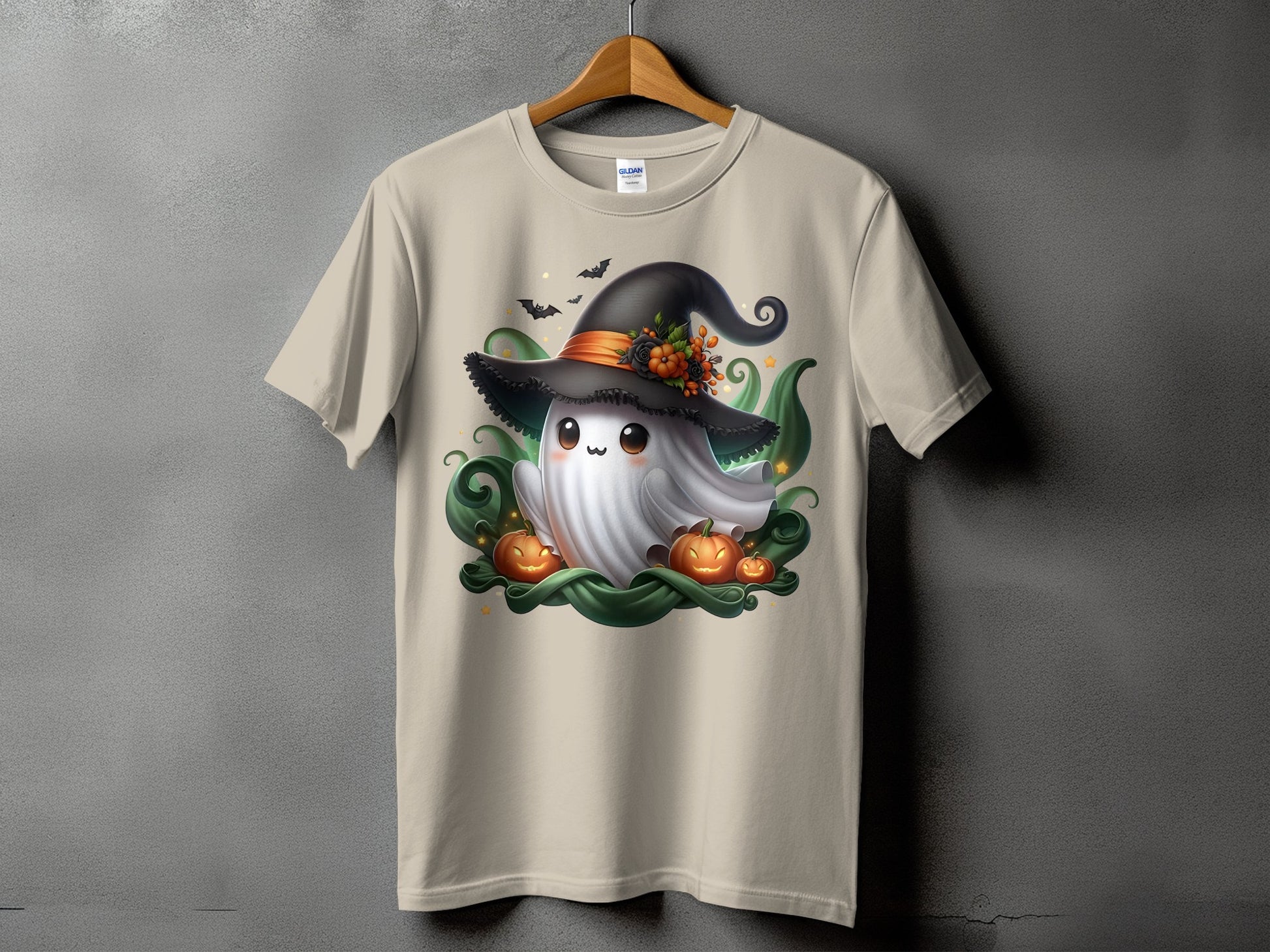 Light tan t-shirt with a cartoon ghost wearing a witch hat and surrounded by pumpkins.