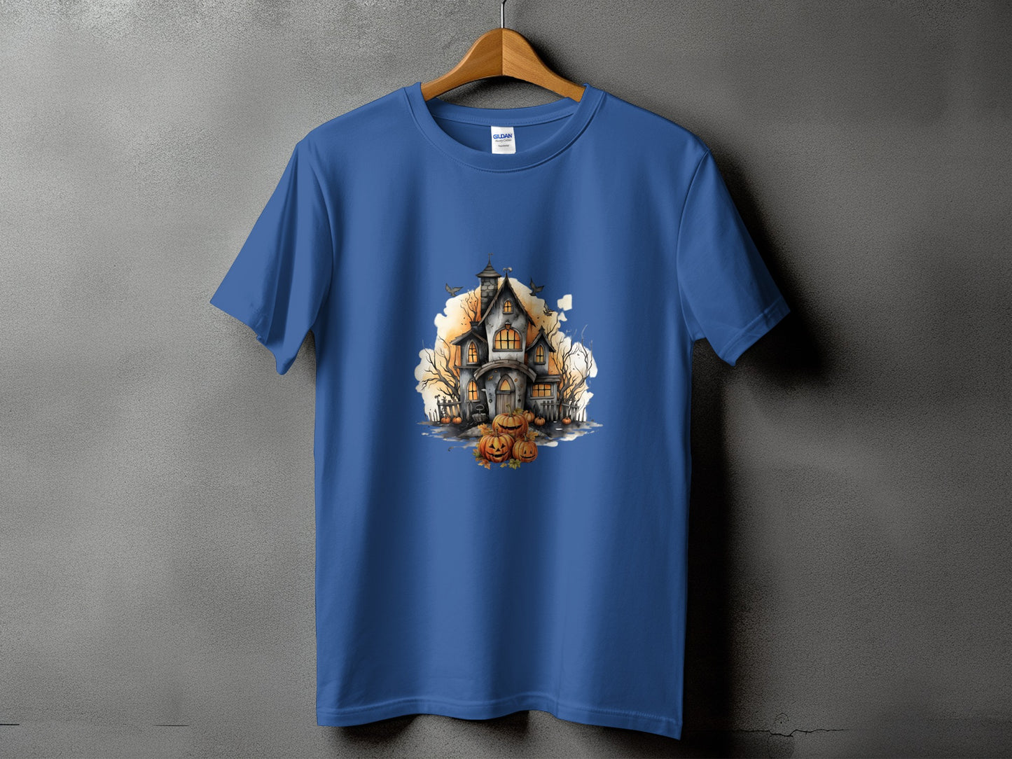 Blue t-shirt with watercolor print of a haunted house, pumpkins, and bare trees.