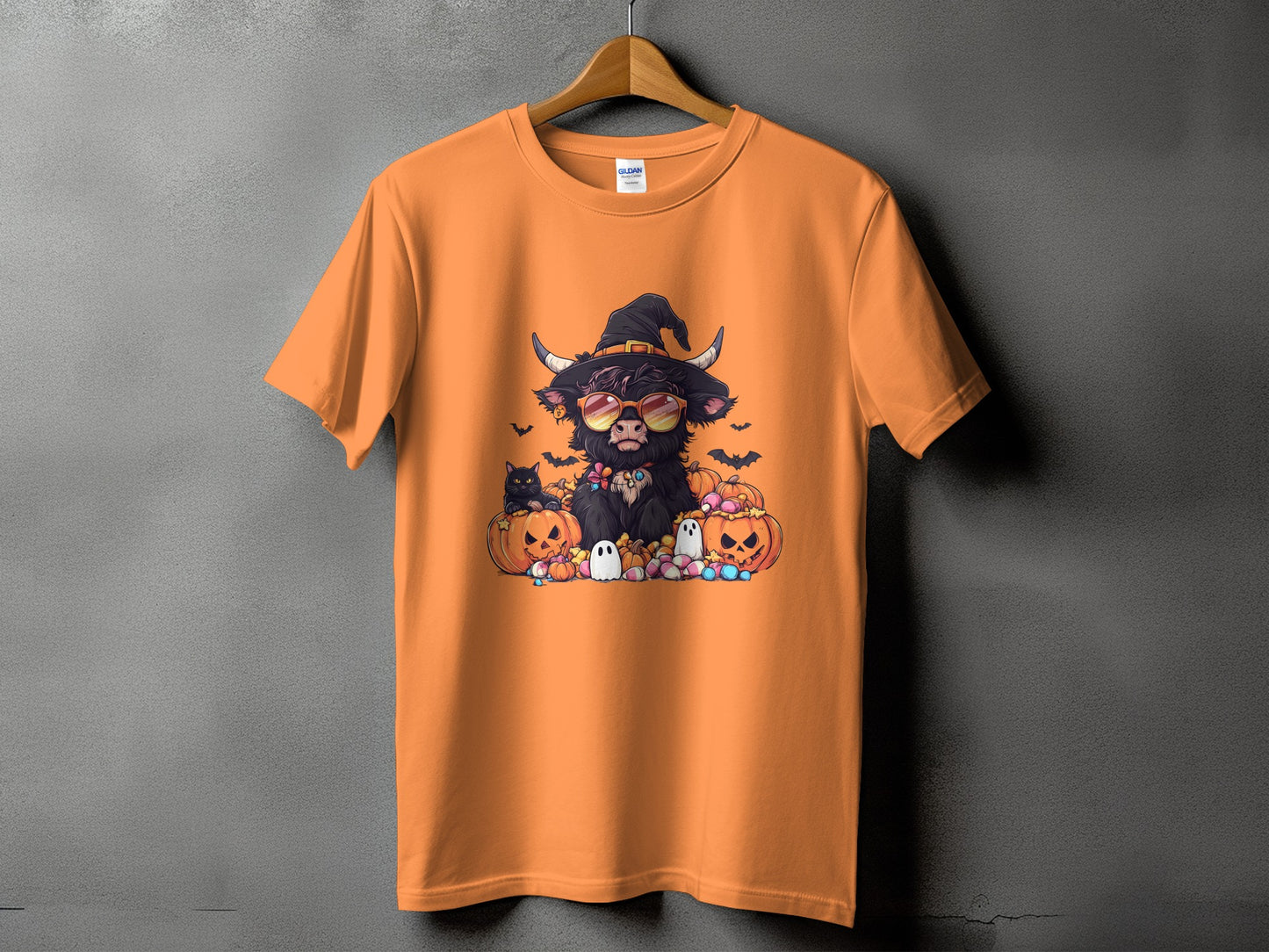 Orange t-shirt with Halloween graphic of a cow wearing a witch hat and sunglasses.