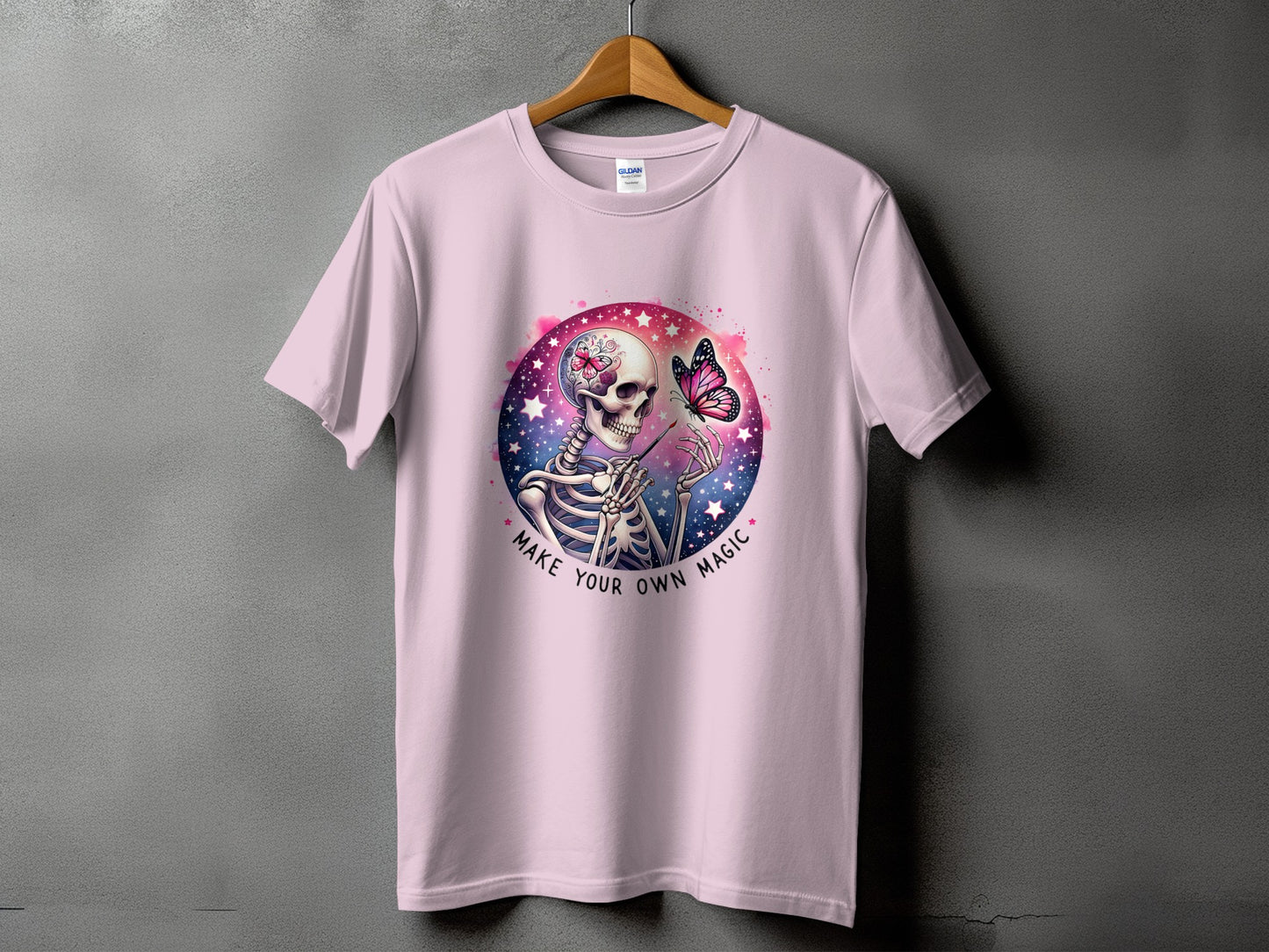Pink t-shirt with skeleton, butterfly, and text "Make Your Own Magic" graphic.