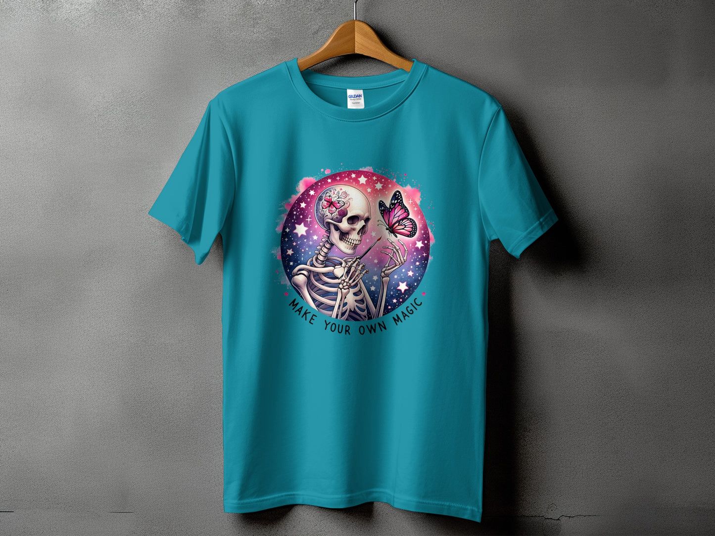 Teal t-shirt with a skeleton painting a butterfly on a starry background.