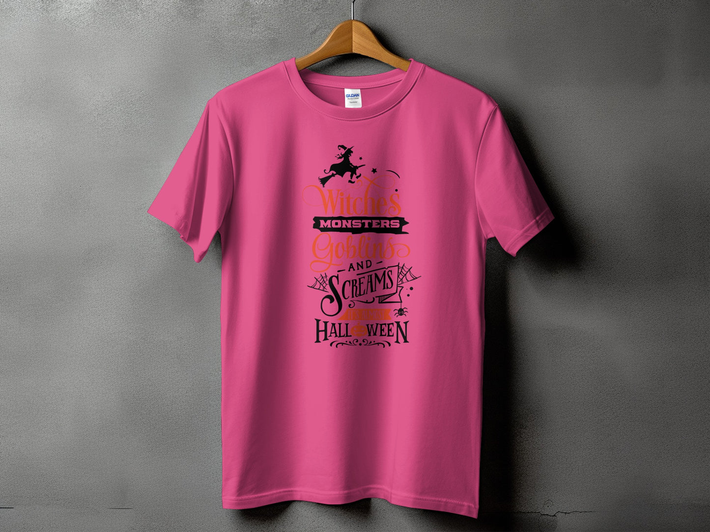 A pink t-shirt hanging on a wooden hanger against a gray textured wall, featuring black Halloween text graphics.