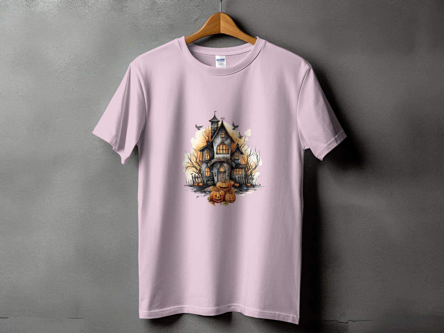 Pink t-shirt featuring a spooky haunted house with pumpkins and birds graphic.