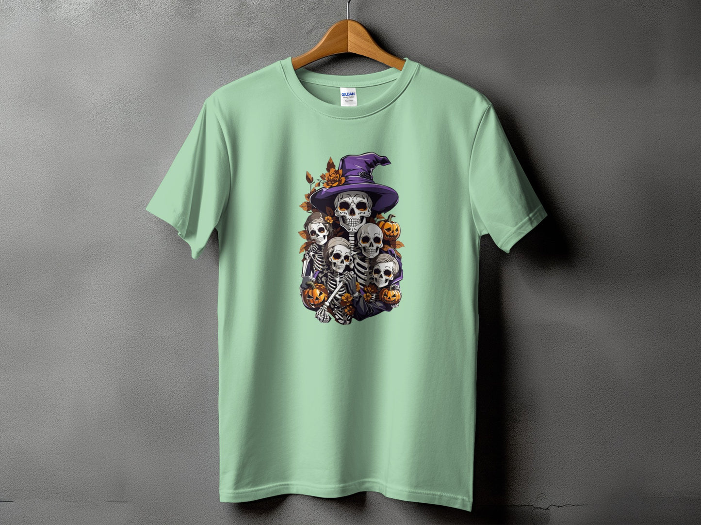 Light green t-shirt with Halloween skeletons and pumpkins graphic print.