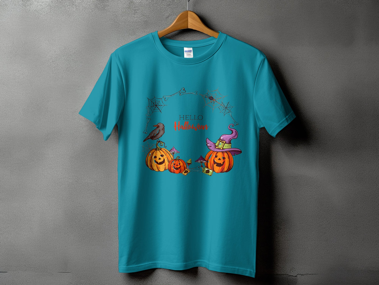 Teal t-shirt with Halloween pumpkins, a witch hat, a bird, and spiders.