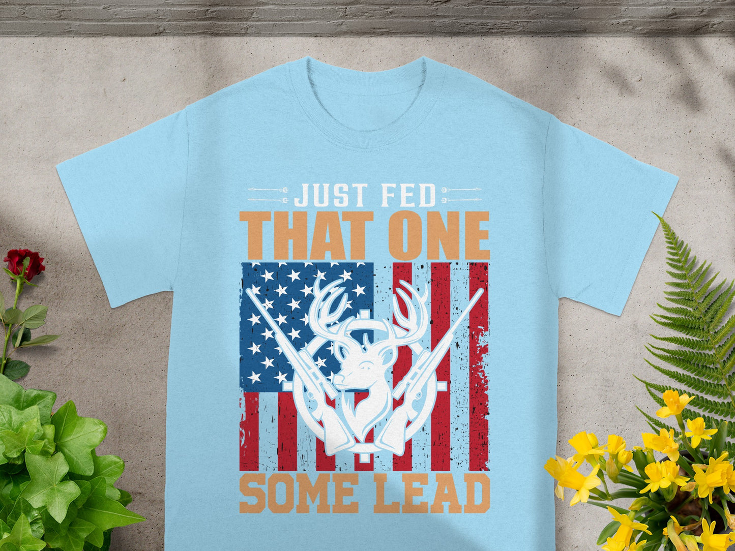 Light blue t-shirt with deer, rifles, and American flag graphic.