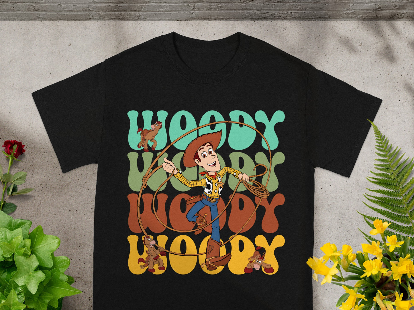 Black t-shirt with Woody from Toy Story and "Woody" in colorful text.