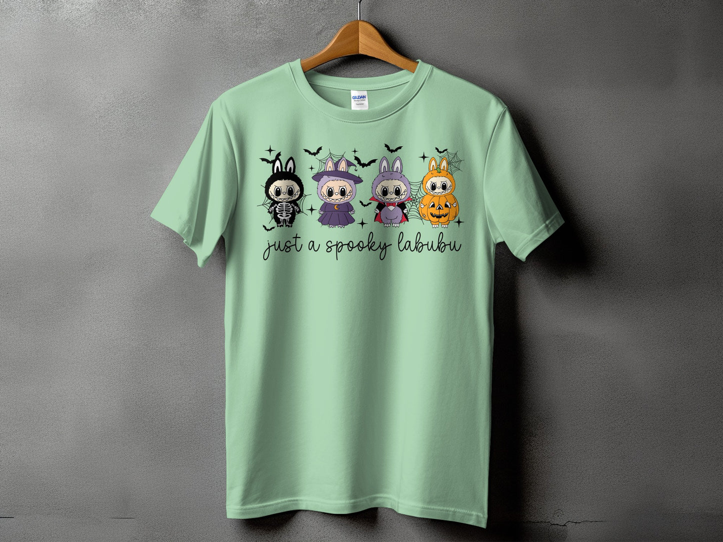 Light green t-shirt with four cartoon characters and "just a spooky labubu" text.