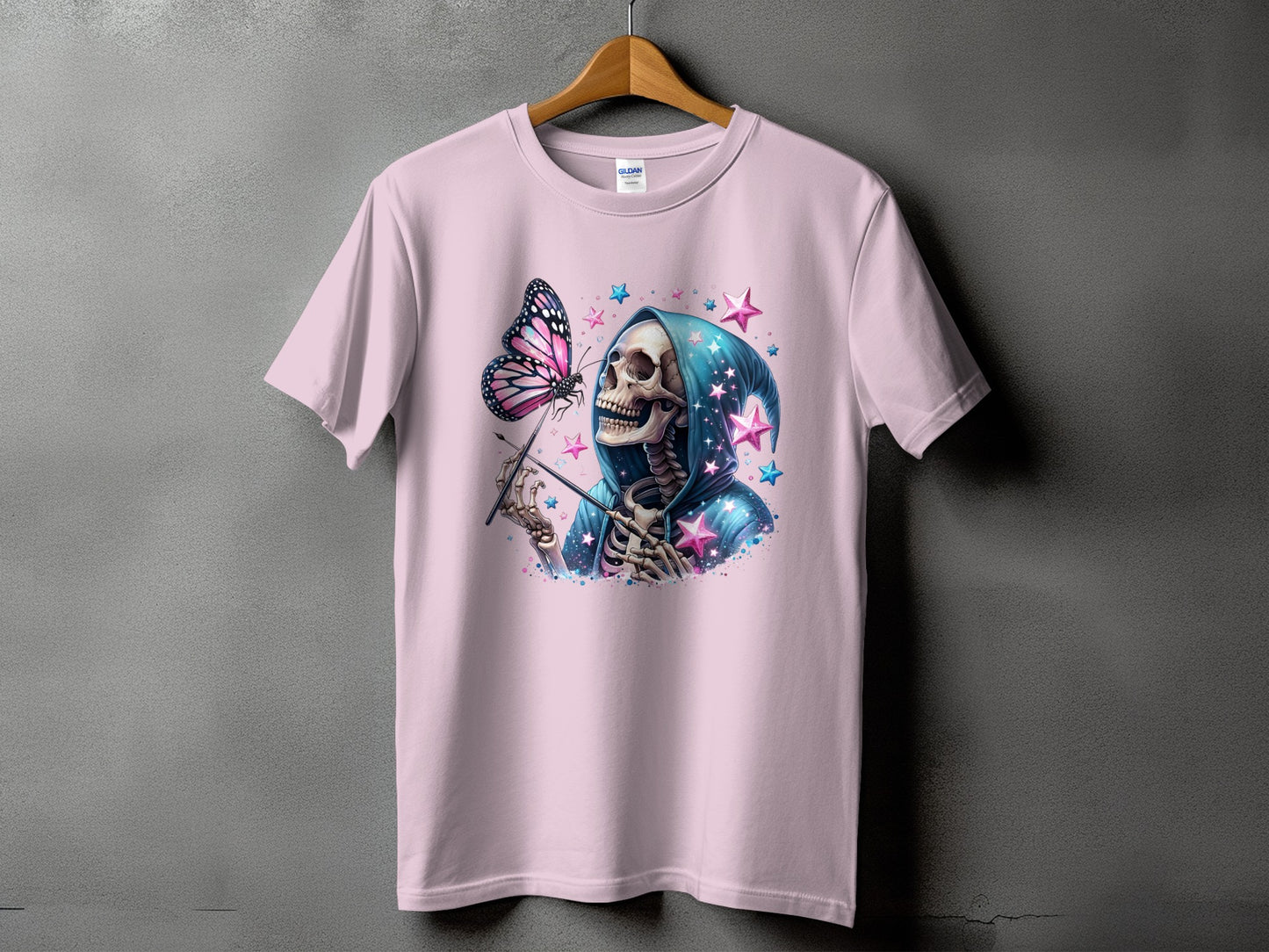 Pink t-shirt with skeleton in blue robe holding wand, butterfly, and stars.