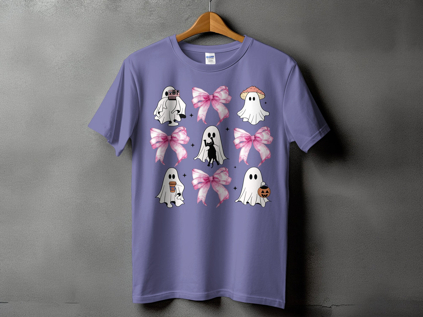 Purple t-shirt with a grid of nine illustrations featuring ghosts, pink bows, and Halloween elements.
