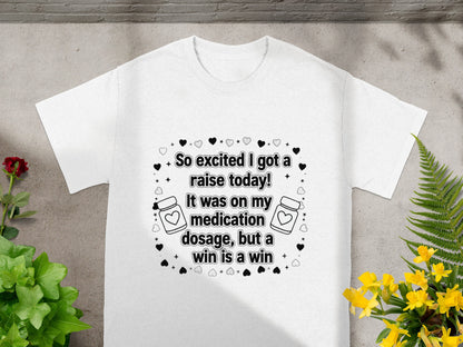 White t-shirt with text "So excited I got a raise today! It was on my medication dosage, but a win is a win."