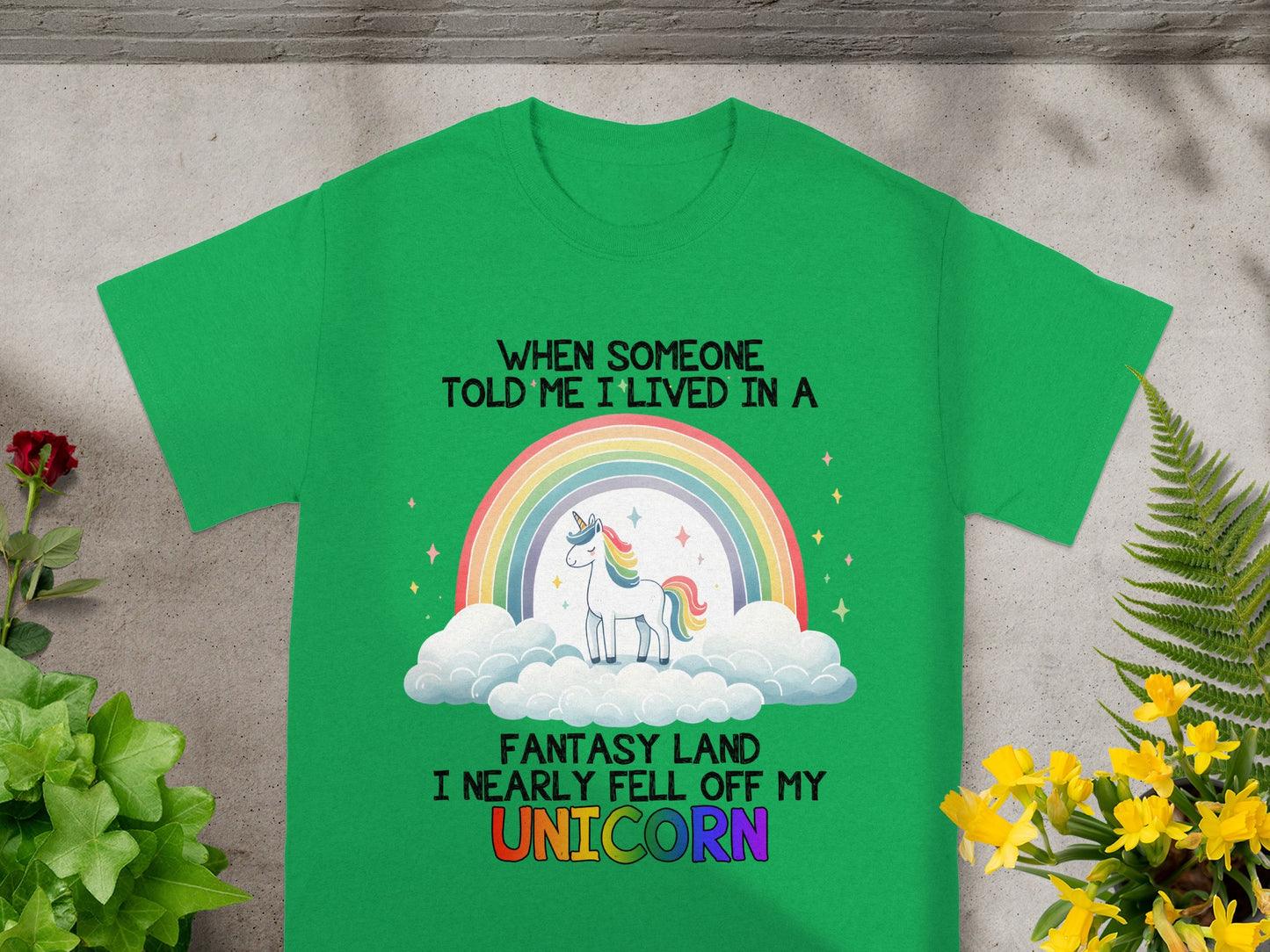 Green t-shirt with a unicorn, rainbow, and text "When someone told me I lived in a fantasy land I nearly fell off my unicorn."